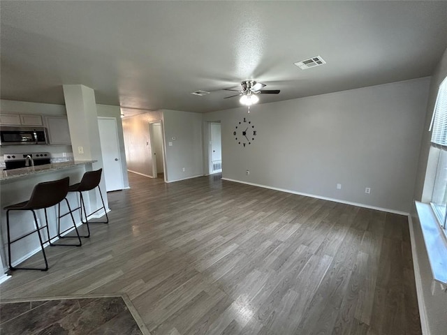 2101 Whistling Way, Taylor, TX 76574 - unfurnished living room featuring dark wood-style floors and ceiling fan