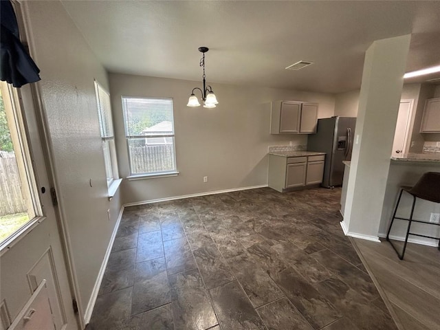 2101 Whistling Way, Taylor, TX 76574 - kitchen featuring stainless steel fridge, a chandelier, light countertops, hanging light fixtures, and a kitchen bar
