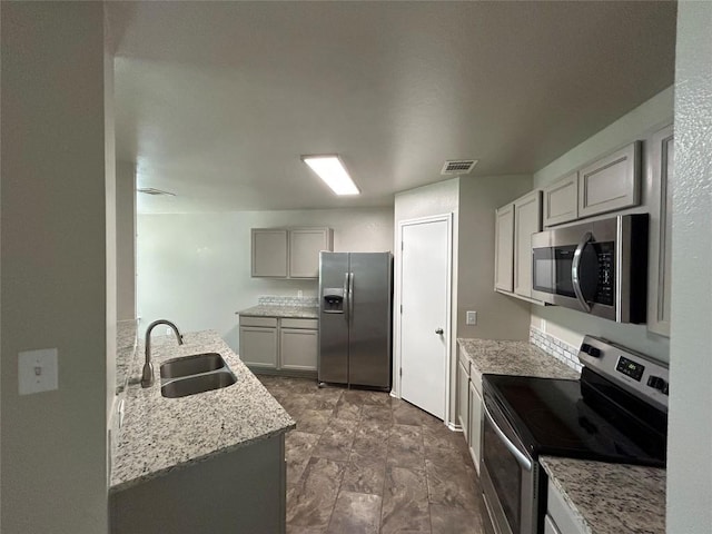 2101 Whistling Way, Taylor, TX 76574 - kitchen featuring stainless steel appliances, light stone countertops, and gray cabinetry
