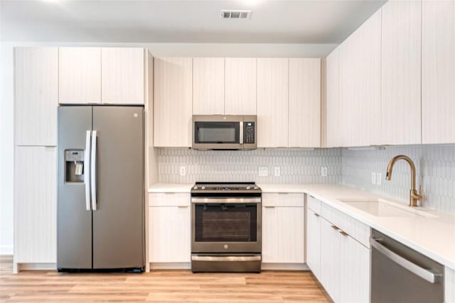 4802 S Congress Ave Unit 217, Austin, TX 78745 - kitchen featuring stainless steel appliances, light countertops, backsplash, and light wood-type flooring
