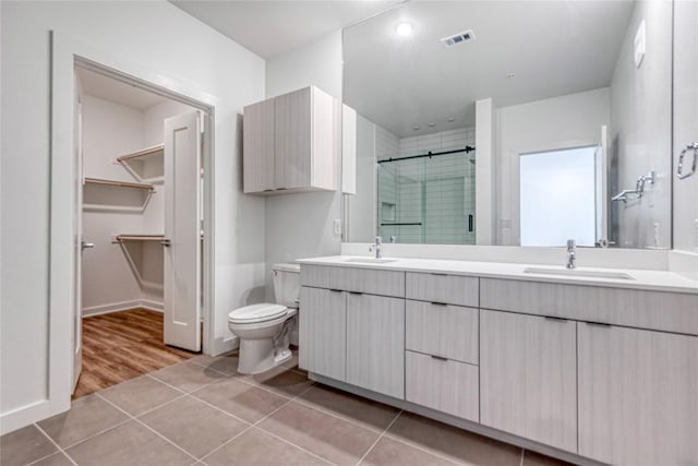 4802 S Congress Ave Unit 217, Austin, TX 78745 - bathroom featuring a shower stall, double vanity, a spacious closet, and tile patterned flooring