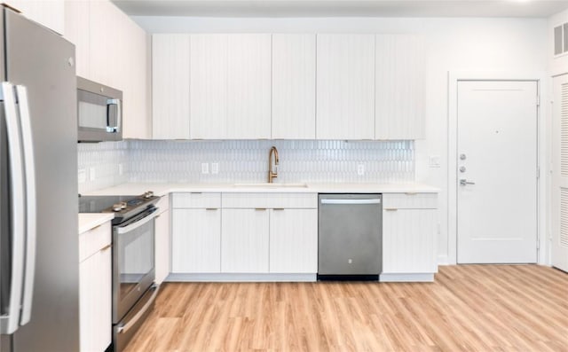 4802 S Congress Ave Unit 217, Austin, TX 78745 - kitchen with stainless steel appliances, light countertops, light wood finished floors, and backsplash