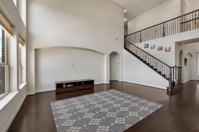 2521 Blended Tree Ranch Dr, Leander, TX 78641 - unfurnished living room with arched walkways, a towering ceiling, stairway, and wood finished floors