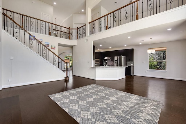 2521 Blended Tree Ranch Dr, Leander, TX 78641 - unfurnished living room featuring dark wood finished floors, stairway, a high ceiling, recessed lighting, and arched walkways