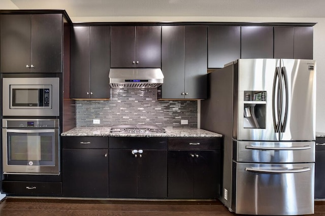 2521 Blended Tree Ranch Dr, Leander, TX 78641 - kitchen with stainless steel appliances, extractor fan, decorative backsplash, dark brown cabinets, and light stone counters