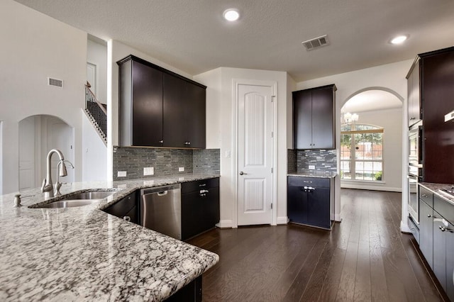 2521 Blended Tree Ranch Dr, Leander, TX 78641 - kitchen with appliances with stainless steel finishes, arched walkways, light stone countertops, dark brown cabinets, and recessed lighting