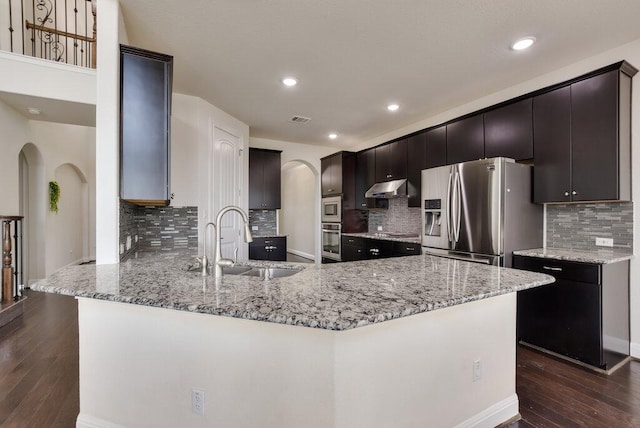 2521 Blended Tree Ranch Dr, Leander, TX 78641 - kitchen featuring arched walkways, stainless steel appliances, a peninsula, dark wood-style flooring, and recessed lighting