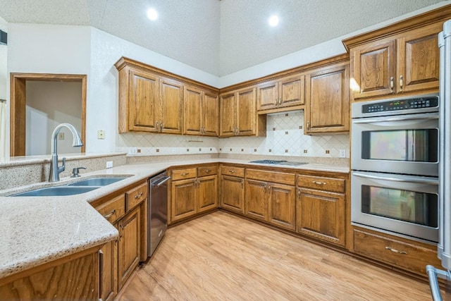 7 Hillway Dr, Round Rock, TX 78664 - kitchen with stainless steel appliances, light wood-style flooring, brown cabinetry, tasteful backsplash, and a textured ceiling