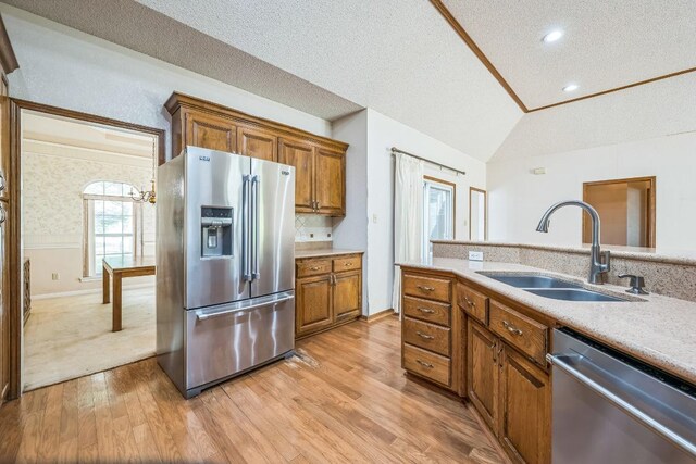 7 Hillway Dr, Round Rock, TX 78664 - kitchen featuring appliances with stainless steel finishes, vaulted ceiling, a textured ceiling, brown cabinetry, and light countertops