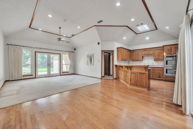 7 Hillway Dr, Round Rock, TX 78664 - kitchen with a peninsula, lofted ceiling, double oven, brown cabinetry, and a breakfast bar area