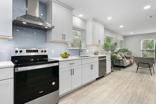 11508 Bell Ave, Austin, TX 78759 - kitchen featuring appliances with stainless steel finishes, wall chimney exhaust hood, light countertops, light wood-type flooring, and backsplash