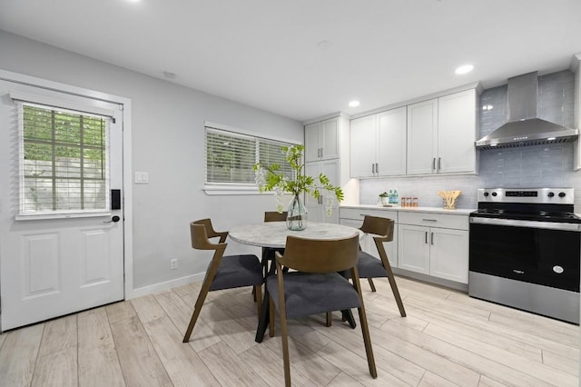 11508 Bell Ave, Austin, TX 78759 - kitchen with stainless steel electric range, wall chimney exhaust hood, light wood-type flooring, decorative backsplash, and light countertops