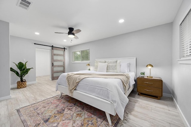 11508 Bell Ave, Austin, TX 78759 - bedroom with a barn door, light wood finished floors, a ceiling fan, and recessed lighting