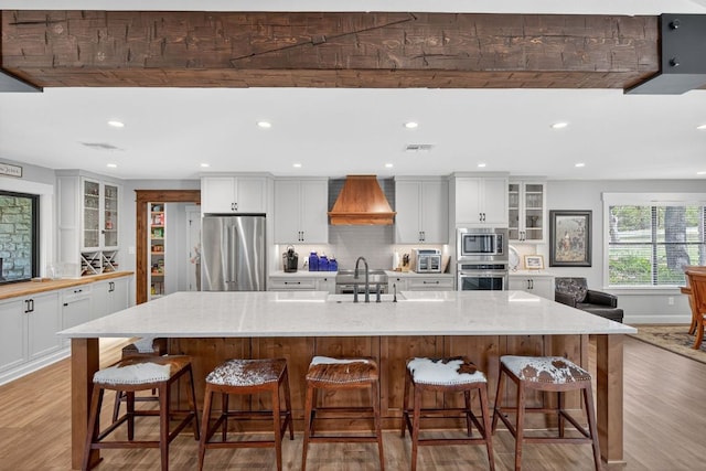 23644 Nameless Rd, Leander, TX 78641 - kitchen with appliances with stainless steel finishes, custom range hood, light wood-style floors, glass insert cabinets, and recessed lighting