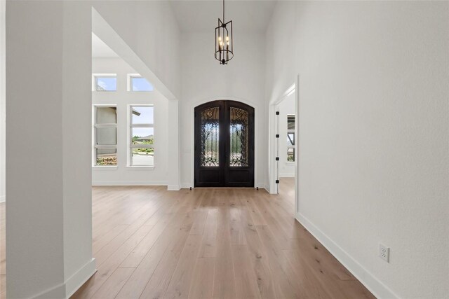 3937 Veneto Cir, Leander, TX 78641 - entryway with a chandelier, french doors, light wood-type flooring, a towering ceiling, and arched walkways