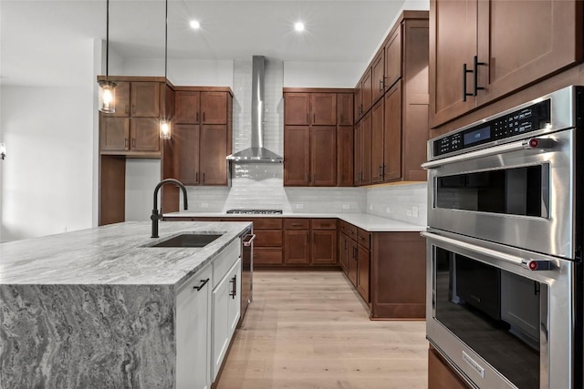 3937 Veneto Cir, Leander, TX 78641 - kitchen featuring appliances with stainless steel finishes, wall chimney exhaust hood, light wood-style flooring, tasteful backsplash, and recessed lighting