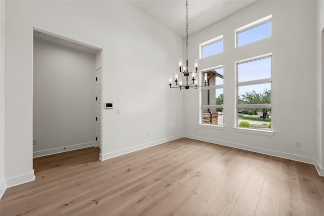 3937 Veneto Cir, Leander, TX 78641 - unfurnished dining area with a chandelier, hardwood / wood-style floors, and a towering ceiling