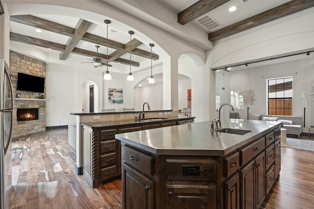 1310 Minnie Dr, Austin, TX 78732 - kitchen featuring stainless steel countertops, open floor plan, an island with sink, beamed ceiling, and arched walkways