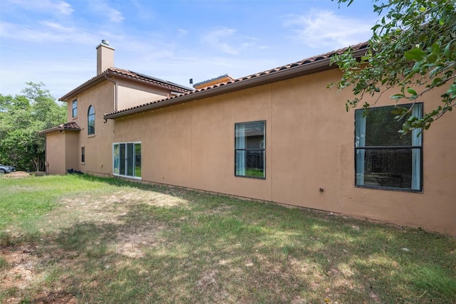 1310 Minnie Dr, Austin, TX 78732 - view of side of home with a chimney, a lawn, stucco siding, and a tile roof