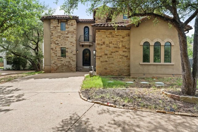 1310 Minnie Dr, Austin, TX 78732 - mediterranean / spanish-style house featuring stone siding, stucco siding, a tiled roof, and concrete driveway