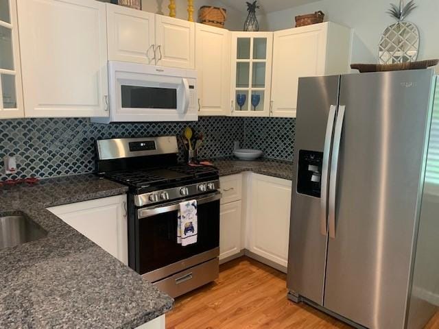 6004 Blythewood Dr, Austin, TX 78745 - kitchen with appliances with stainless steel finishes, light wood-type flooring, white cabinetry, and decorative backsplash