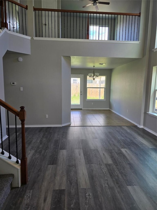9615 Fratelli Ct, Killeen, TX 76542 - unfurnished living room featuring a towering ceiling, a chandelier, dark wood-style flooring, stairs, and ceiling fan