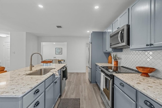 837 Mica Ln, Leander, TX 78641 - kitchen featuring appliances with stainless steel finishes, backsplash, light stone countertops, light wood-style floors, and recessed lighting