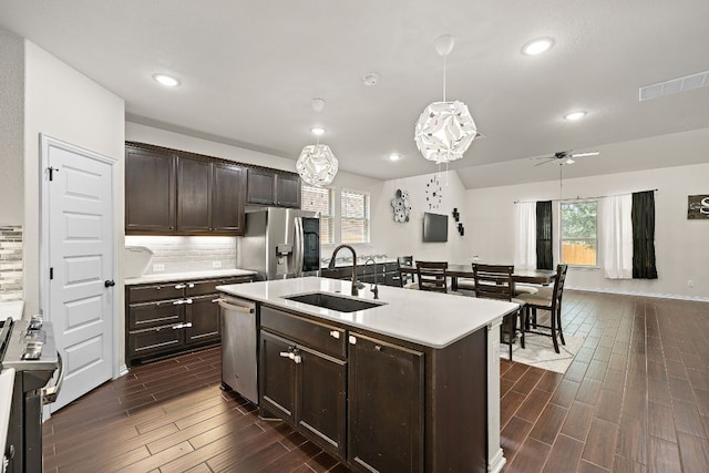 2433 Roaring River Trl, Leander, TX 78641 - kitchen featuring appliances with stainless steel finishes, dark wood-type flooring, dark brown cabinetry, light countertops, and healthy amount of natural light