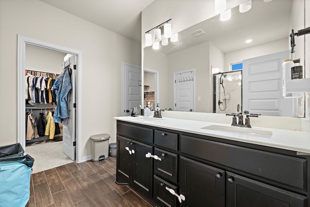 2433 Roaring River Trl, Leander, TX 78641 - bathroom with a walk in closet, double vanity, wood finished floors, and a shower stall