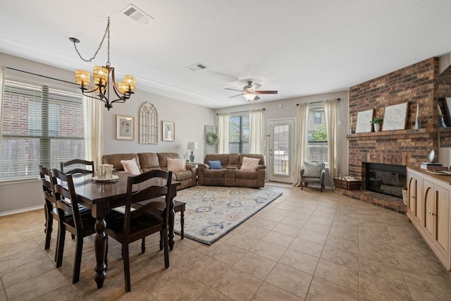 901 Water Hyacinth Loop, Leander, TX 78641 - dining area featuring light tile patterned floors, a chandelier, a brick fireplace, and ceiling fan