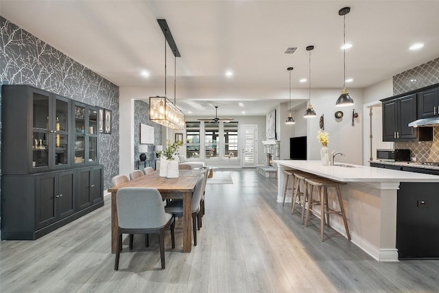 225 Escarpment Way, Cedar Park, TX 78613 - dining space with an accent wall, a ceiling fan, light wood-style flooring, wallpapered walls, and recessed lighting