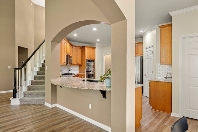 2604 Zambia Dr, Cedar Park, TX 78613 - kitchen featuring appliances with stainless steel finishes, crown molding, light wood-style floors, backsplash, and a peninsula