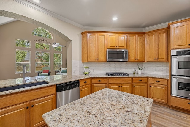 2604 Zambia Dr, Cedar Park, TX 78613 - kitchen featuring appliances with stainless steel finishes, light stone counters, ornamental molding, arched walkways, and light wood-type flooring