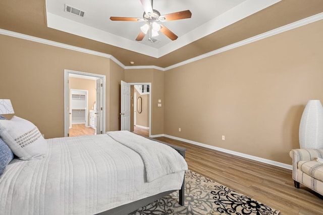 2604 Zambia Dr, Cedar Park, TX 78613 - bedroom featuring a tray ceiling, wood finished floors, a ceiling fan, and connected bathroom