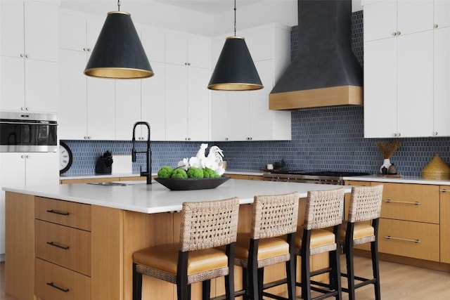 2005 Far Gallant Dr, Austin, TX 78746 - kitchen with premium range hood, tasteful backsplash, light countertops, a breakfast bar area, and a kitchen island with sink