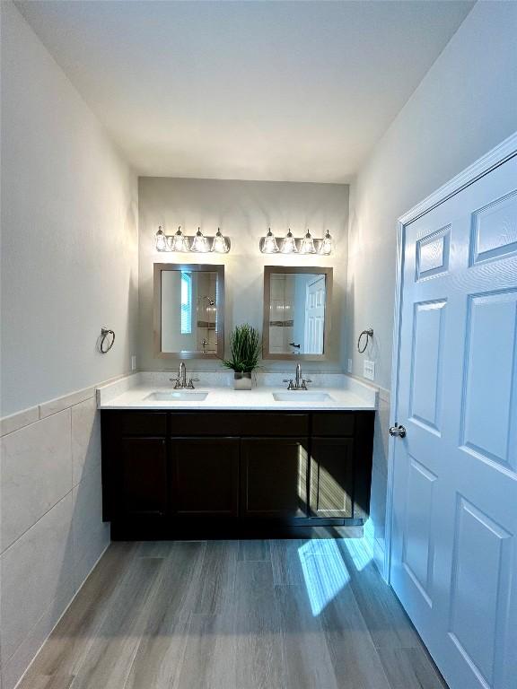 3805 E US-290 Hwy E, Paige, TX 78659 - bathroom with double vanity, tile walls, wood finished floors, and wainscoting