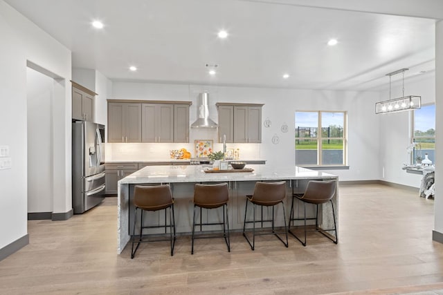 311 Out Crop, Horseshoe Bay, TX 78657 - kitchen featuring stainless steel refrigerator with ice dispenser, wall chimney exhaust hood, gray cabinetry, a kitchen bar, and recessed lighting
