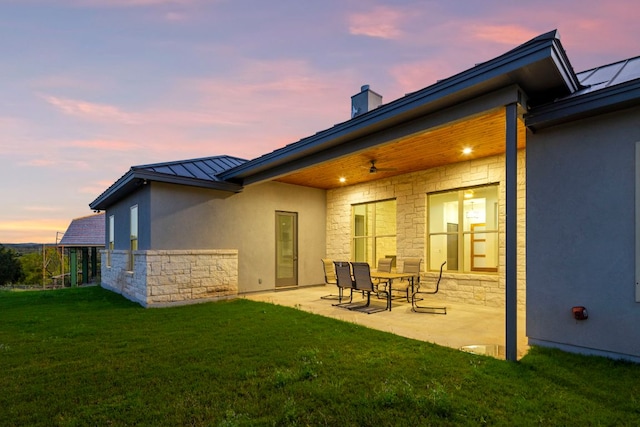 311 Out Crop, Horseshoe Bay, TX 78657 - back of property at dusk featuring a standing seam roof, stone siding, a patio area, and stucco siding