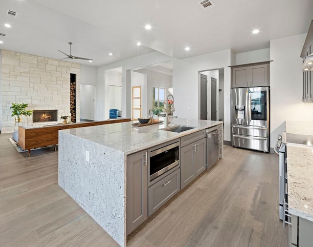 311 Out Crop, Horseshoe Bay, TX 78657 - kitchen featuring stainless steel appliances, gray cabinetry, light wood finished floors, an island with sink, and a ceiling fan
