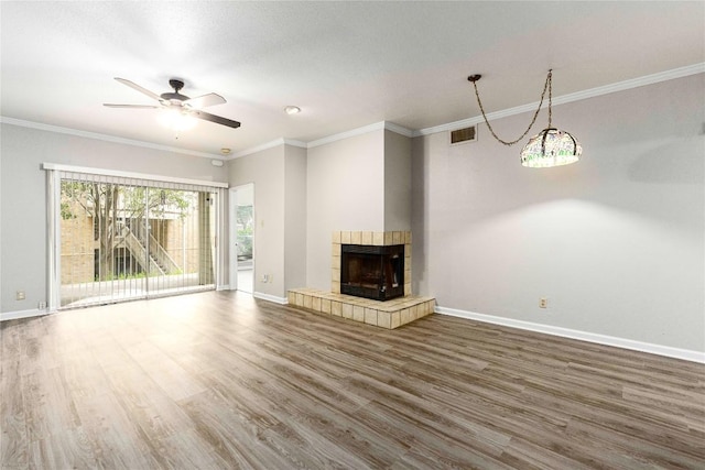 2450 Wickersham Ln Unit 1001, Austin, TX 78741 - unfurnished living room featuring wood finished floors, a tile fireplace, a ceiling fan, and crown molding