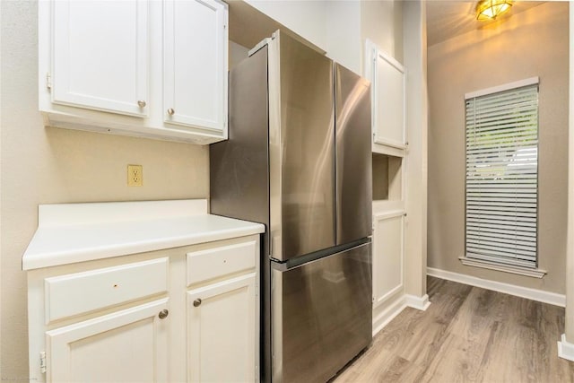 2450 Wickersham Ln Unit 1001, Austin, TX 78741 - kitchen with freestanding refrigerator, light wood-style flooring, light countertops, and white cabinets