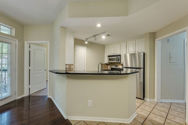9525 N Capital Of Texas Hwy Unit 414, Austin, TX 78759 - kitchen featuring stainless steel appliances, dark countertops, white cabinetry, decorative backsplash, and a peninsula