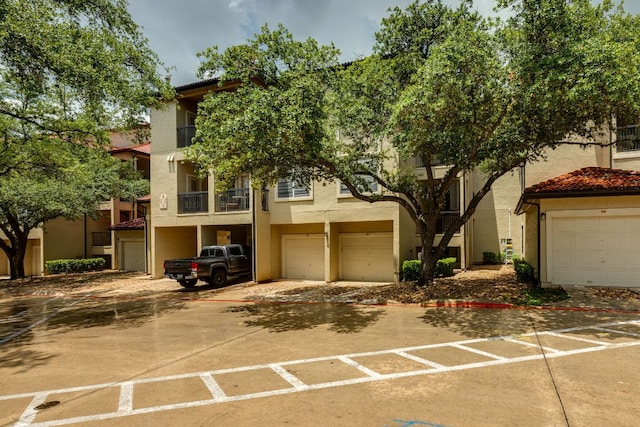 9525 N Capital Of Texas Hwy Unit 414, Austin, TX 78759 - view of front of house with stucco siding, an attached garage, a tile roof, and a balcony