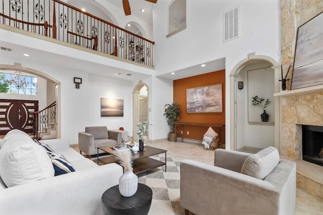 7608 Journeyville Dr, Austin, TX 78735 - tiled living area featuring arched walkways, a high ceiling, a fireplace, stairway, and recessed lighting