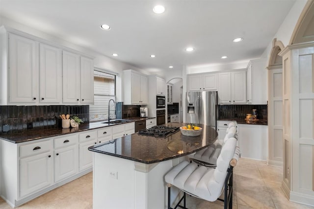 7608 Journeyville Dr, Austin, TX 78735 - kitchen featuring appliances with stainless steel finishes, backsplash, arched walkways, white cabinetry, and a kitchen island