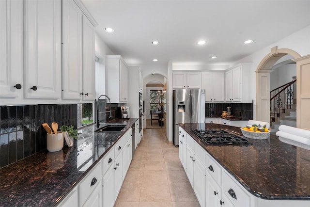 7608 Journeyville Dr, Austin, TX 78735 - kitchen with arched walkways, appliances with stainless steel finishes, backsplash, recessed lighting, and white cabinetry