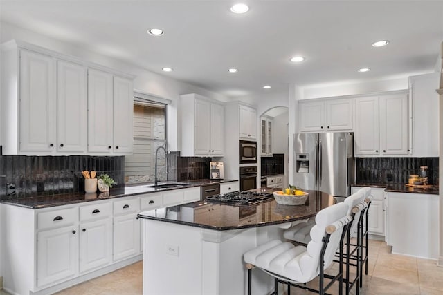 7608 Journeyville Dr, Austin, TX 78735 - kitchen with black appliances, decorative backsplash, white cabinets, a kitchen island, and arched walkways