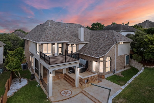 7608 Journeyville Dr, Austin, TX 78735 - back of property at dusk with a balcony, a chimney, a patio area, roof with shingles, and a yard
