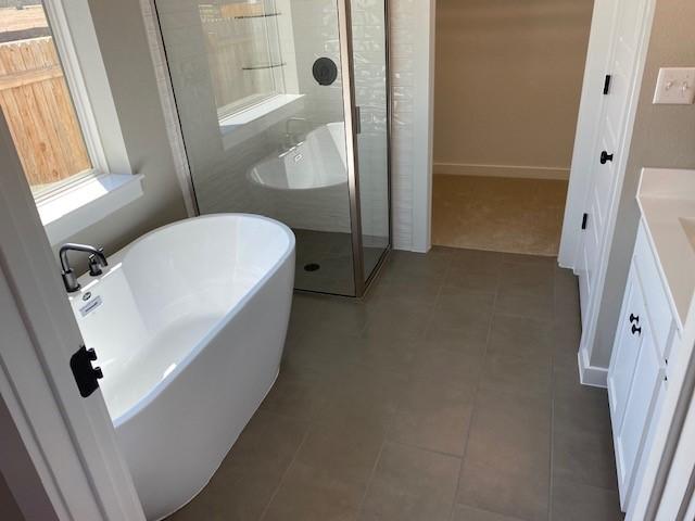 303 Watercourse Way, Bastrop, TX 78602 - bathroom with vanity, a stall shower, a freestanding bath, and tile patterned floors