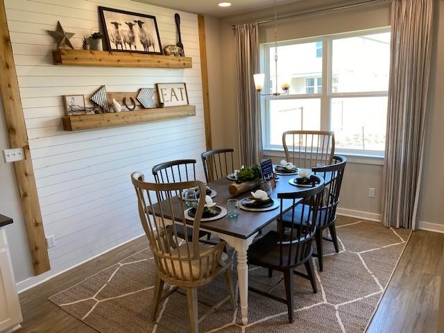 303 Watercourse Way, Bastrop, TX 78602 - dining space with dark wood-type flooring, a chandelier, and wood walls